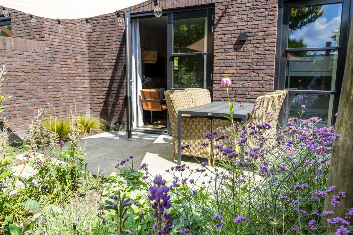 Terras tussen groene beplanting en paarse bloemen