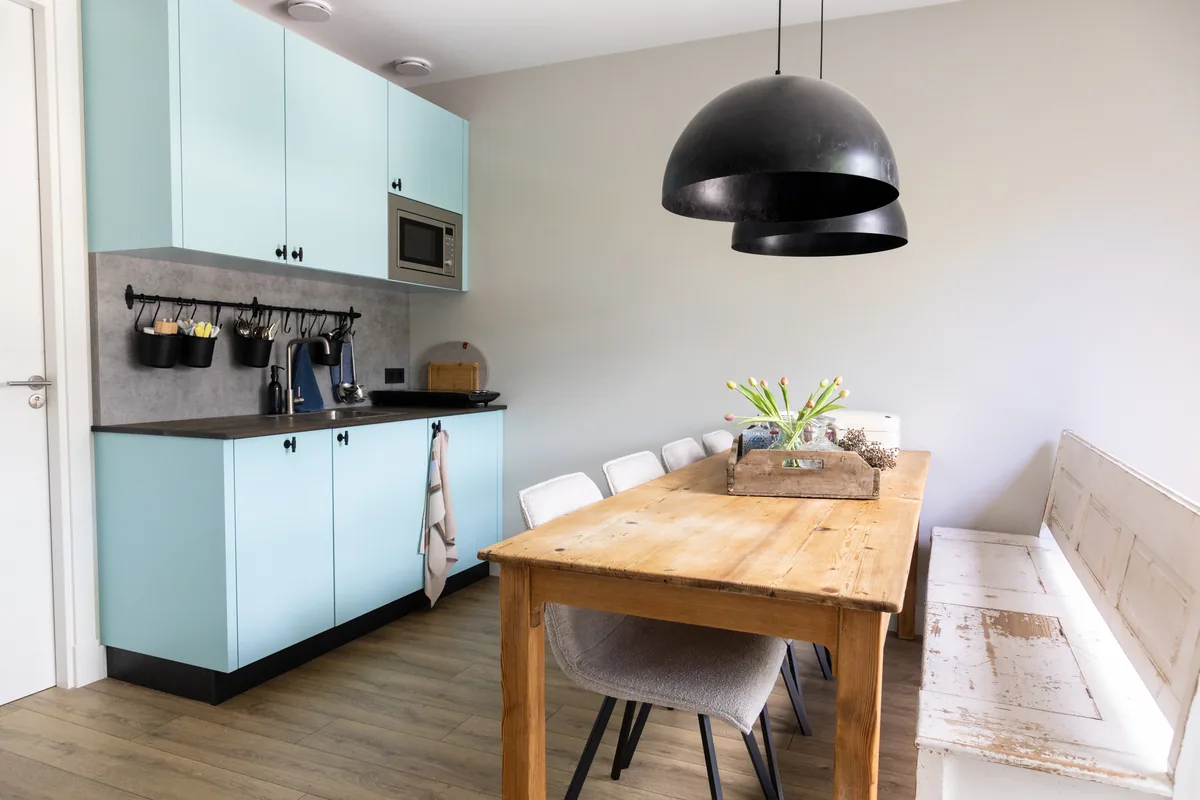 Lichtblauwe keuken met houten eettafel